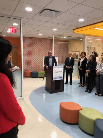 Andreas Dracopoulos, co-president of the Stavros Niarchos Foundation, gives a speech at Montefiore while people surround him and listen